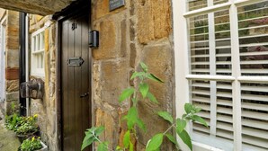 A stone cottage with a dark wooden door, a sign reading "Cottage Ducklington," and a window with white shutters. - Cottage in Whitby near Stunning Beaches (Whitby)