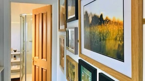 A hallway with framed pictures on the wall, a wooden door, and a glass door leading to a room with a plant. - Apartment in Matlock near River Derwent (Matlock)