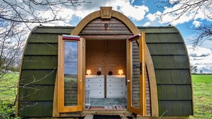 A wooden cabin with a sloped roof, two open doors, and a small porch area.