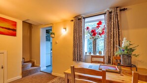 Un comedor con una mesa y sillas de madera, una ventana con cortinas y vistas al exterior.