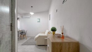 A modern kitchen with a wooden countertop, a dining area with a table and chairs, and a sofa.
