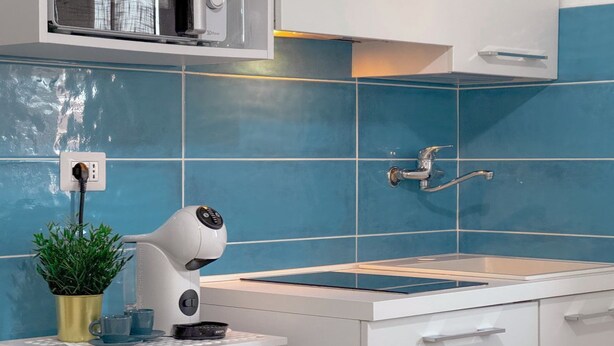 A modern kitchen with blue tiles, a built-in oven, and a sink.