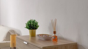 A wooden bedside table with a potted plant, a bowl, and a reed diffuser.