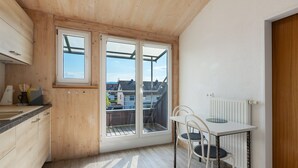 A kitchen with wooden cabinets, a dining table with chairs, and a view through large windows. - Holiday Apartment 'Hannelore' with Shared Garden, Balcony and Wi-Fi (Radolfzell am Bodensee)