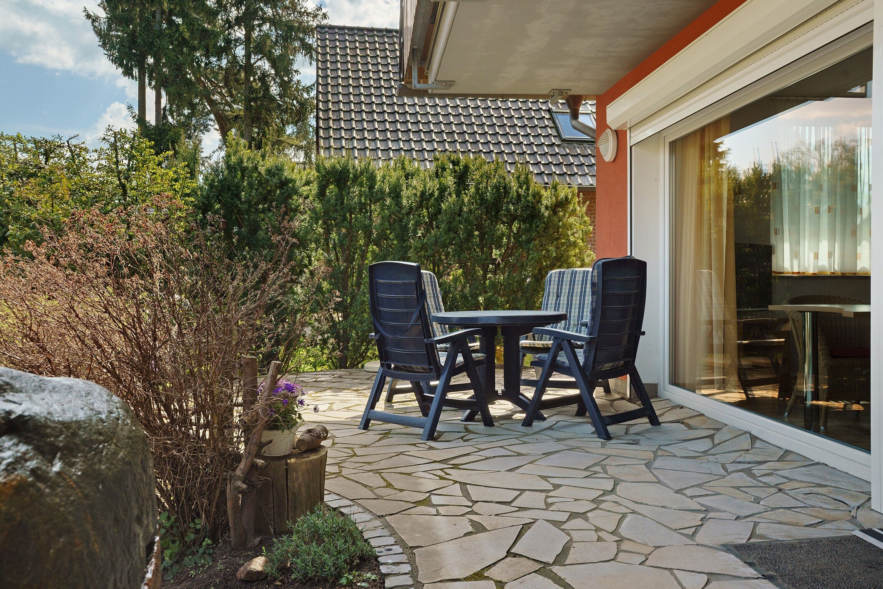 An outdoor patio with stone flooring, two chairs, and a table.