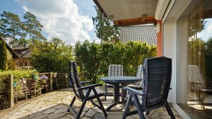 Eine Terrasse mit Steinböden, zwei Stühlen, einem Tisch und einem Holzzaun.