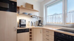 Et moderne køkken med indbygget mikroovn, kaffemaskine og opvaskemaskine.