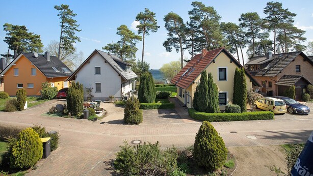 En boligvej med huse, parkerede biler og en klar himmel.