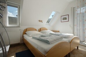 Een slaapkamer met een bed, een raam, een radiator en een plafondlamp.