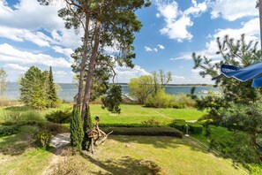 A view of a lake with a wooden dock, surrounded by trees and a well-maintained lawn. - Apartment 'Hs13og mit Müritzblick' with Lake View, Private Garden and Wi-Fi (Röbel/Müritz)