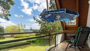 Parveke, josta avautuu näkymä järvelle, pöytä ja tuolit sekä sininen aurinkovarjo, jossa on teksti ”Augustiner-Bräu München”.
