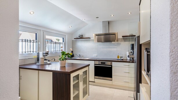 A modern kitchen with a central island, stainless steel appliances, and a window with a view. - Apartment 'New Look' with Mountain View, Balcony and Wi-Fi (Geisenheim)