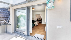 A modern interior with a sliding glass door leading to a dining area, a visible electrical outlet, and a wall-mounted light fixture. - Apartment 'New Look' with Mountain View, Balcony and Wi-Fi (Geisenheim)