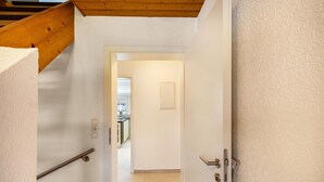 A hallway with a wooden ceiling, a white door with a handle, and a white wall. - Apartment 'New Look' with Mountain View, Balcony and Wi-Fi (Geisenheim)