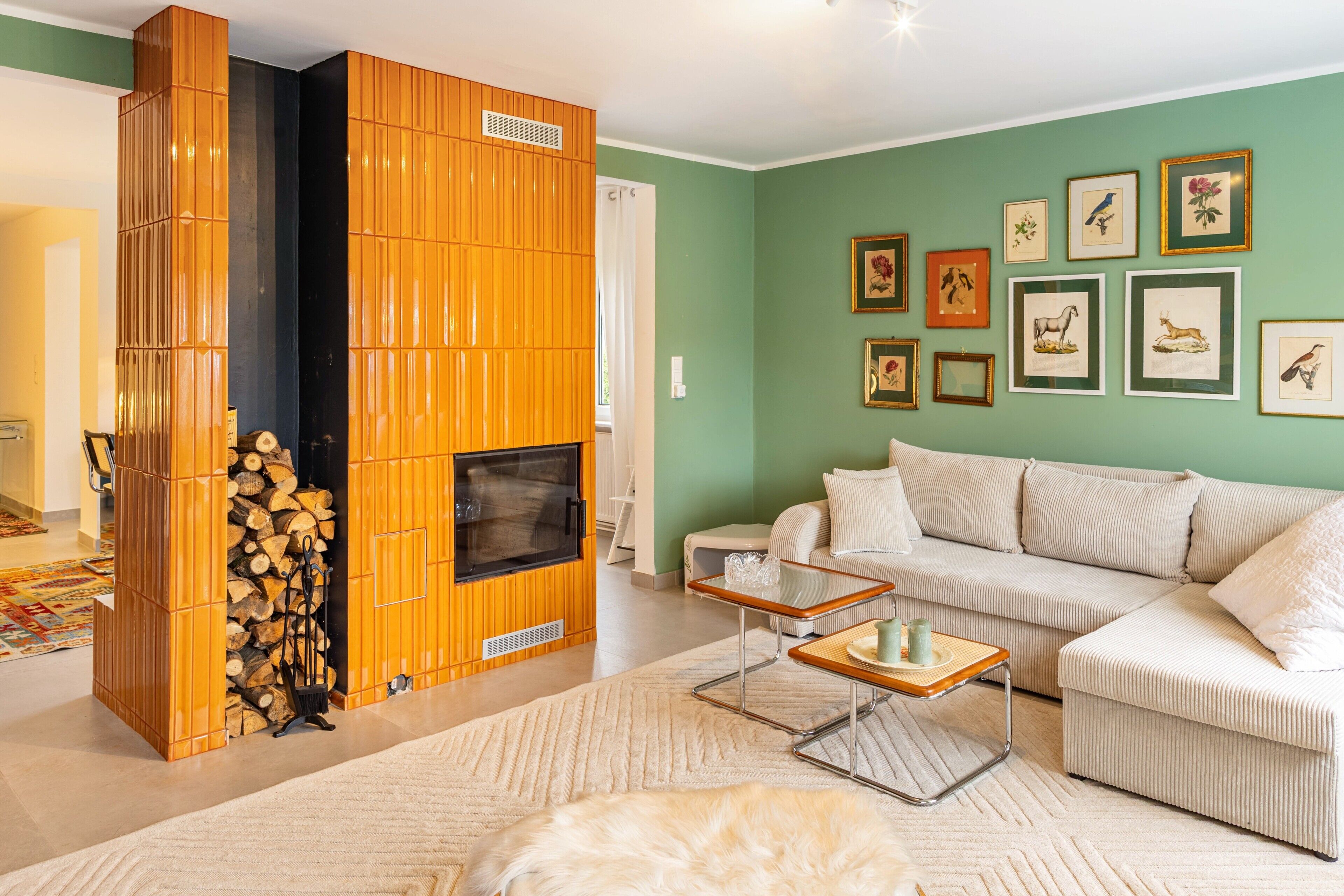 Ein Wohnzimmer mit einer Couch, einem Couchtisch, einem Kamin und gerahmten Bildern an der Wand.