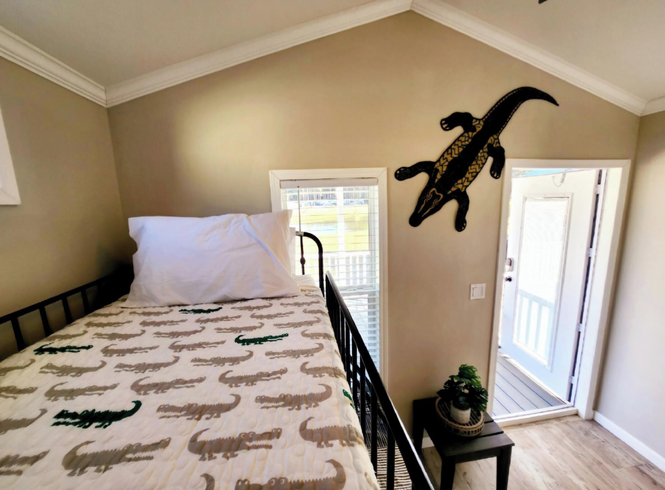 Un dormitorio con cama, ventana, puerta y un adorno en la pared.