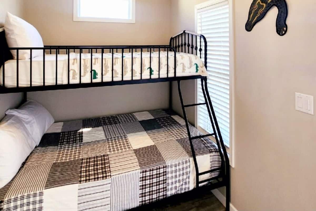 Une chambre avec un lit superposé, un ventilateur de plafond, une fenêtre et un élément de décoration murale.