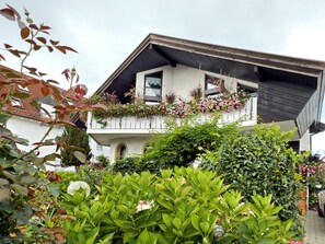 Una casa de dos pisos con un balcón decorado con flores y plantas.