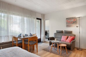 Un salon moderne avec un canapé, une table à manger et des chaises, une lampe sur pied et un tableau accroché au mur.