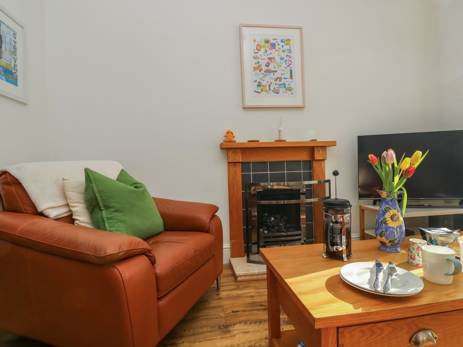 Una sala de estar con un sofá de cuero marrón, una mesa de centro de madera, una chimenea y un televisor.