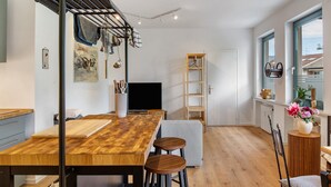 Een moderne keuken met een houten aanrecht, krukken, een droogrek en een televisie.