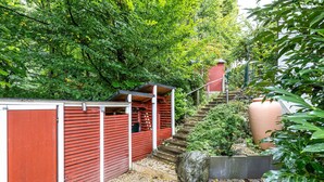 A red wooden fence, a stone planter, and a staircase leading to a red building. - Studio 'Remke' with Private Terrace and Wi-Fi (Starnberg)