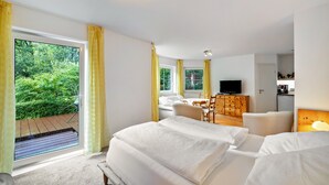 A bedroom with a large window, a bed, a TV, and a wooden desk. - Studio 'Remke' with Private Terrace and Wi-Fi (Starnberg)