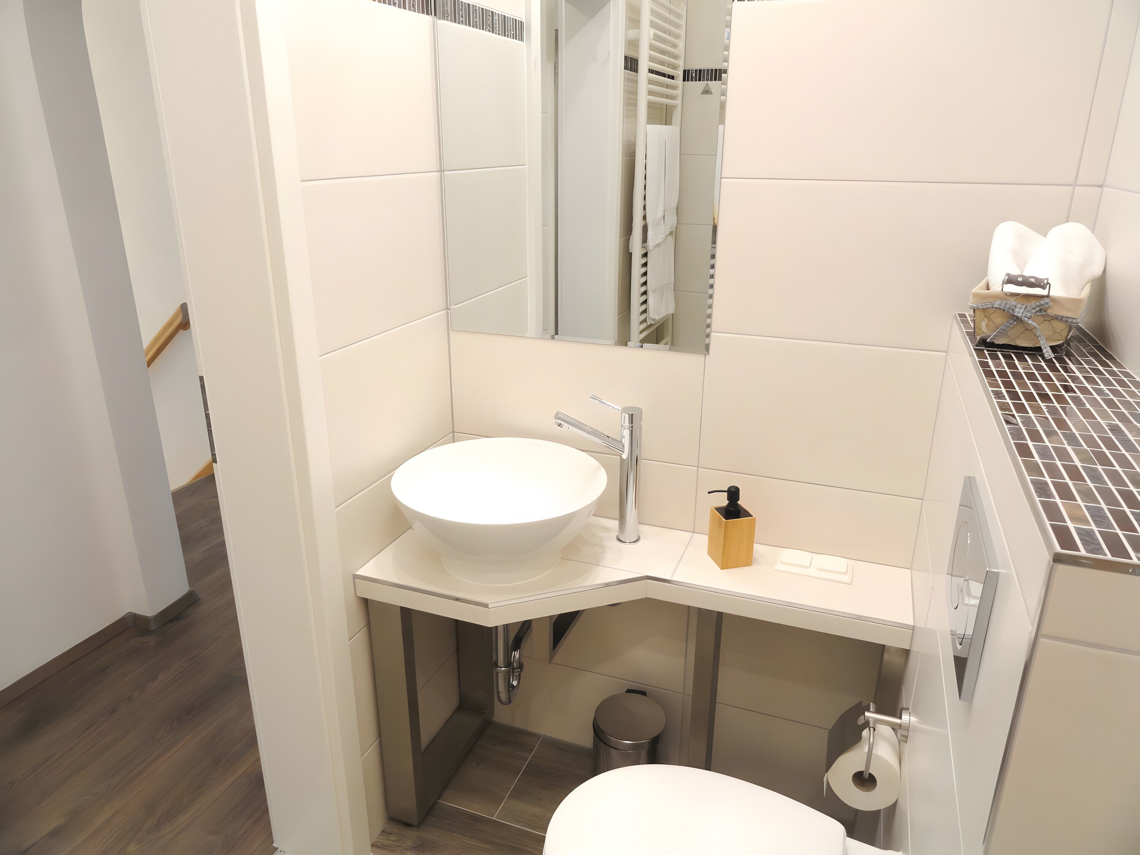 A modern bathroom with a white sink, mirror, and toilet.