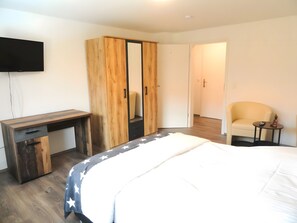 A bedroom with a bed, a desk, a wardrobe, a chair, and a small table. - Apartment 'Karins Pension Room 4' with Wi-Fi (Lampertheim)