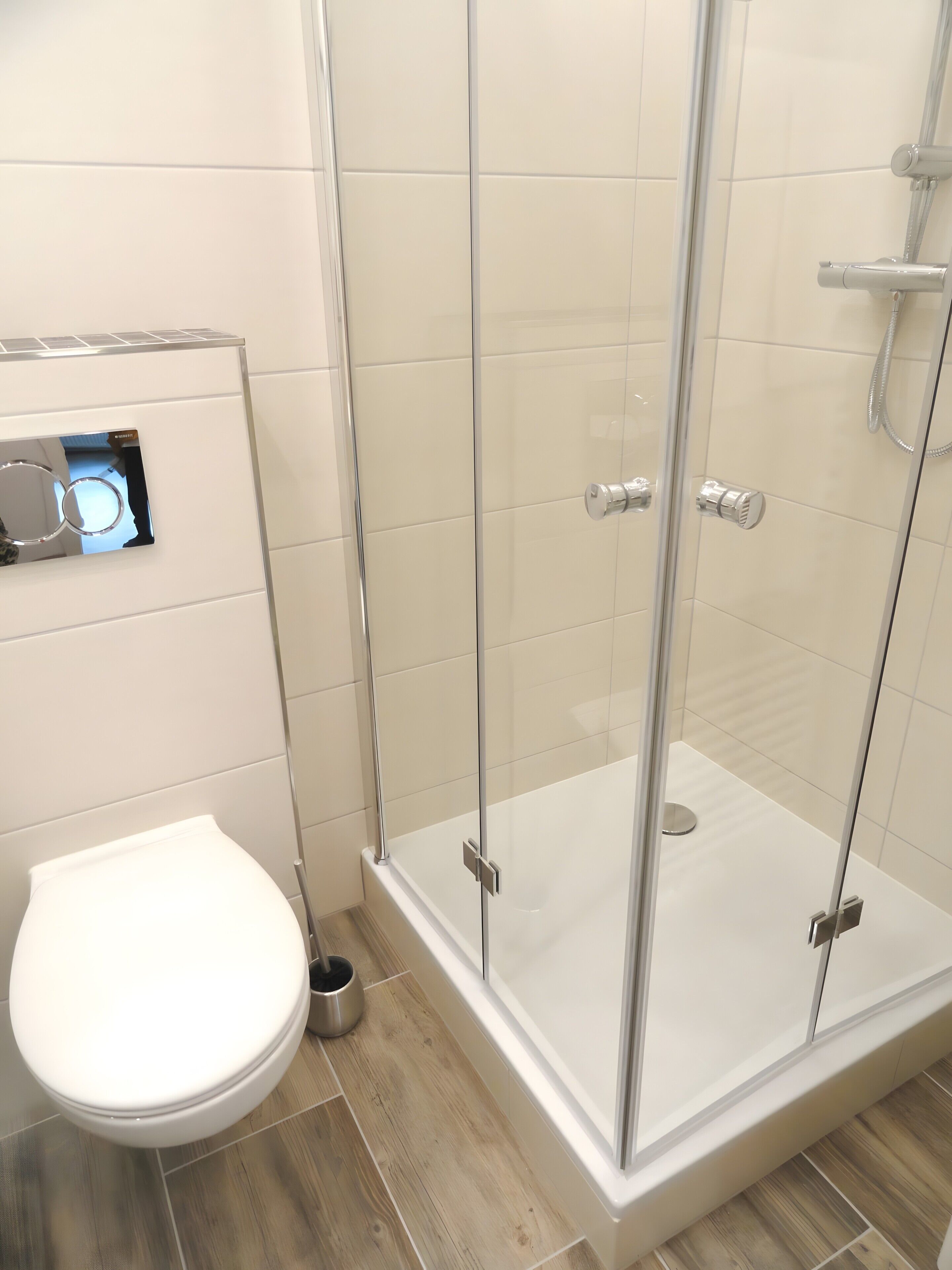 A modern bathroom with a glass-enclosed shower, a toilet, and a bidet.
