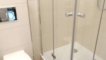 A modern bathroom with a glass-enclosed shower, a toilet, and a bidet.