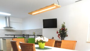 Un comedor moderno con sillas de mimbre, una mesa blanca y un jarrón verde con flores.