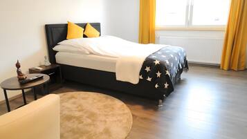 A bedroom with a bed, bedside table, and a small table with a remote control.