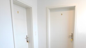 Dos puertas blancas con los números 2 y 3, un piso de madera y una pared blanca.