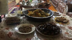 A dining area with a round table set for a meal, surrounded by sofas and chairs. - Gite ditabe tafoukte  (Imi N'Oulaoune)