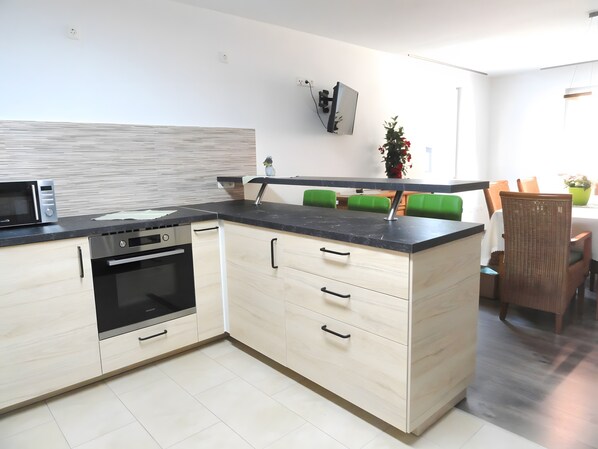 A modern kitchen with a built-in oven, a microwave, and a black countertop.