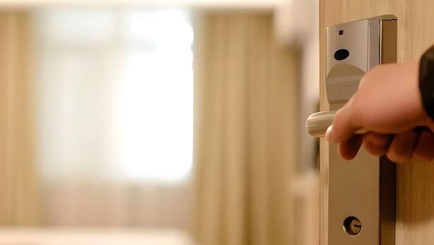 Una mano operando una cerradura moderna en una habitación de hotel.