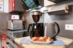A kitchen with a coffee maker, a microwave, a toaster, and a bowl of fruit on the counter.