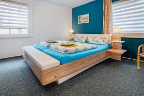 A bedroom with a bed, bedside tables, a lamp, and a window with blinds.