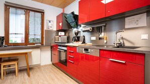 Une cuisine moderne avec des meubles de rangement rouges, un four à micro-ondes, un four traditionnel et une machine à café.
