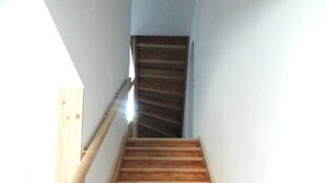 Una escalera de madera con barandilla que conduce a una puerta en la parte superior.