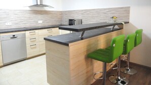 Una cocina moderna con una isla central, taburetes de bar y lavavajillas.