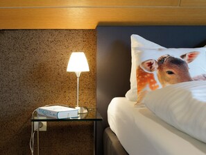 Een hotelkamer met een bed, een nachtkastje met een lamp en een boek.