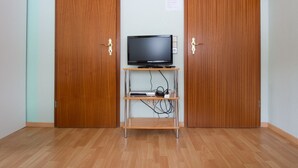 Ett rum med två trägarderober, en tv på ett stativ och en liten hylla med elektronisk utrustning.