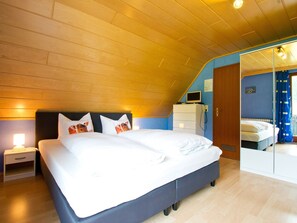 Un dormitorio con cama, mesita de noche, cómoda y espejo.