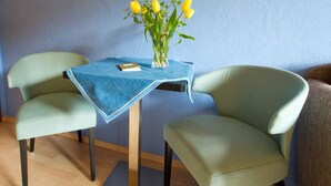 A room with two chairs, a small table, and a vase with yellow flowers. - Room 'Julia' with Shared Terrace, Balcony and Wi-Fi (Bad Rippoldsau-Schapbach)