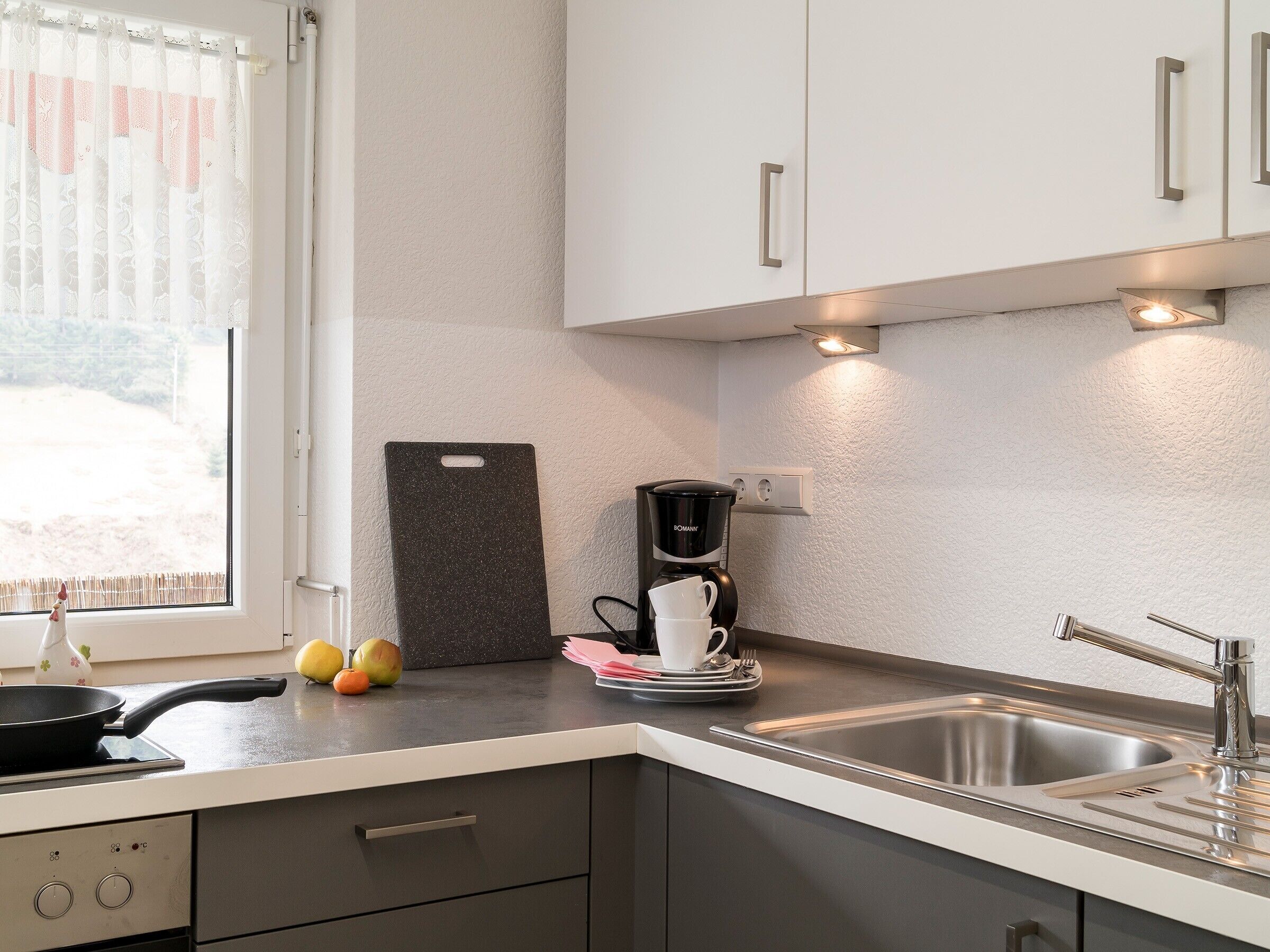 A modern kitchen with a built-in stove, a coffee maker, and a sink.