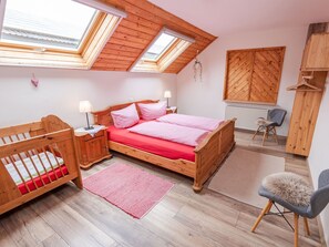 Une chambre à coucher avec un lit en bois, un berceau, une chaise et un radiateur.