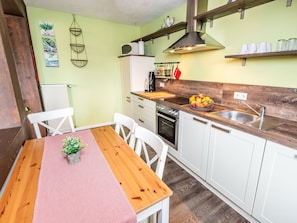 A kitchen with white cabinets, a wooden table, a sink, and a hanging light fixture.