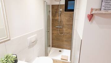 Ein kleines Badezimmer mit Dusche, Toilette und Waschbecken.